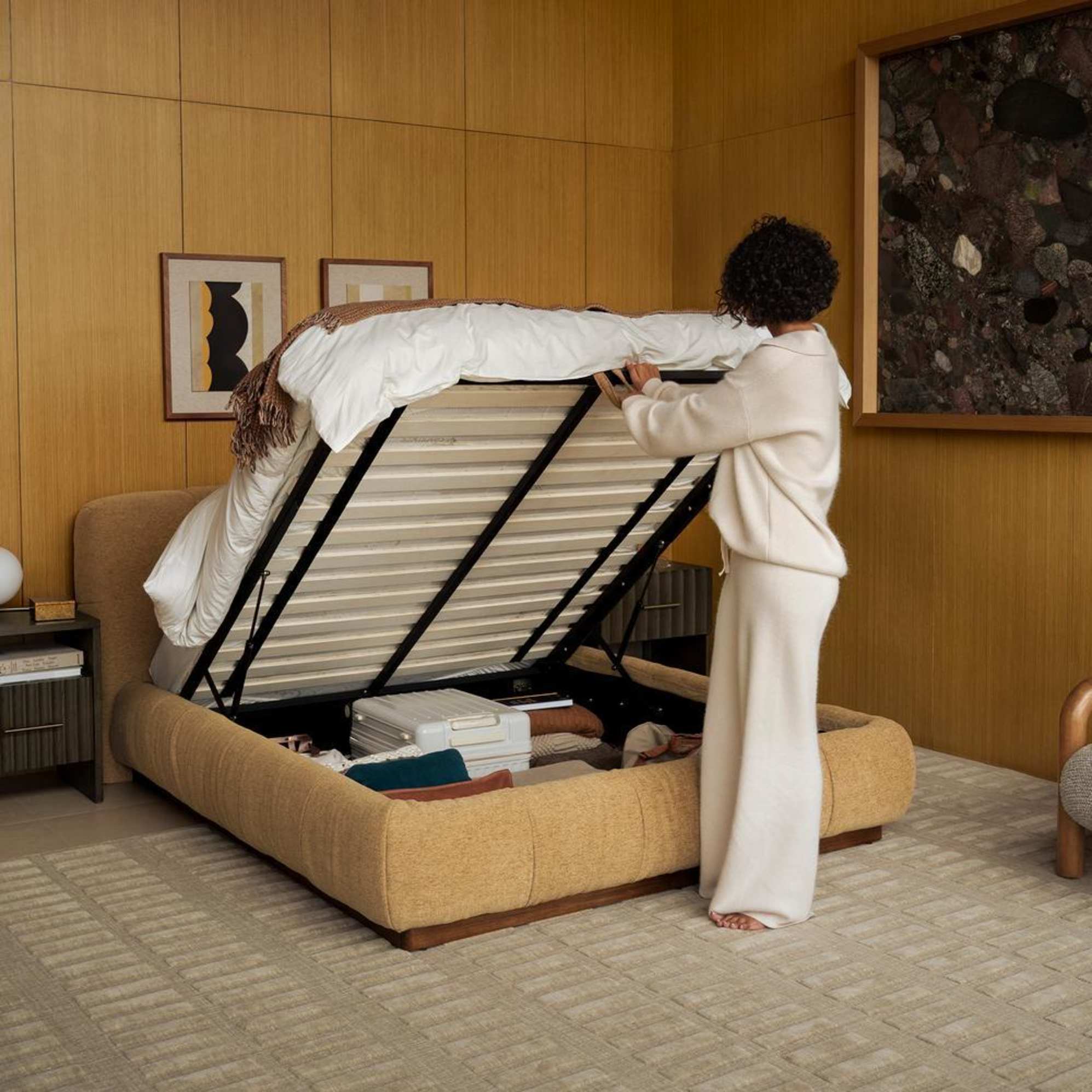 A woman lifting up a hydraulic-lift bed to reveal storage beneath.