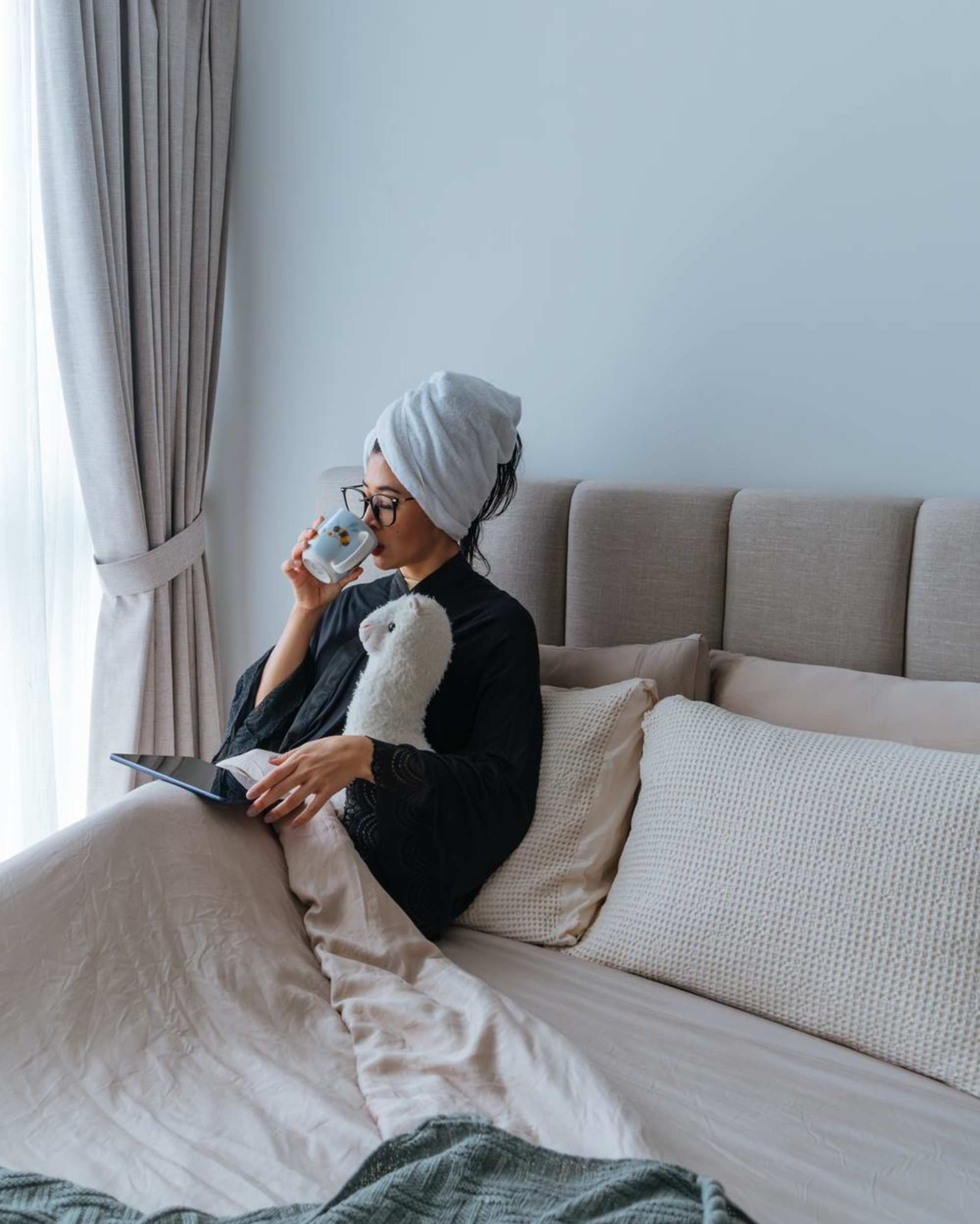 A woman sitting on a bed with a tufted headboard.