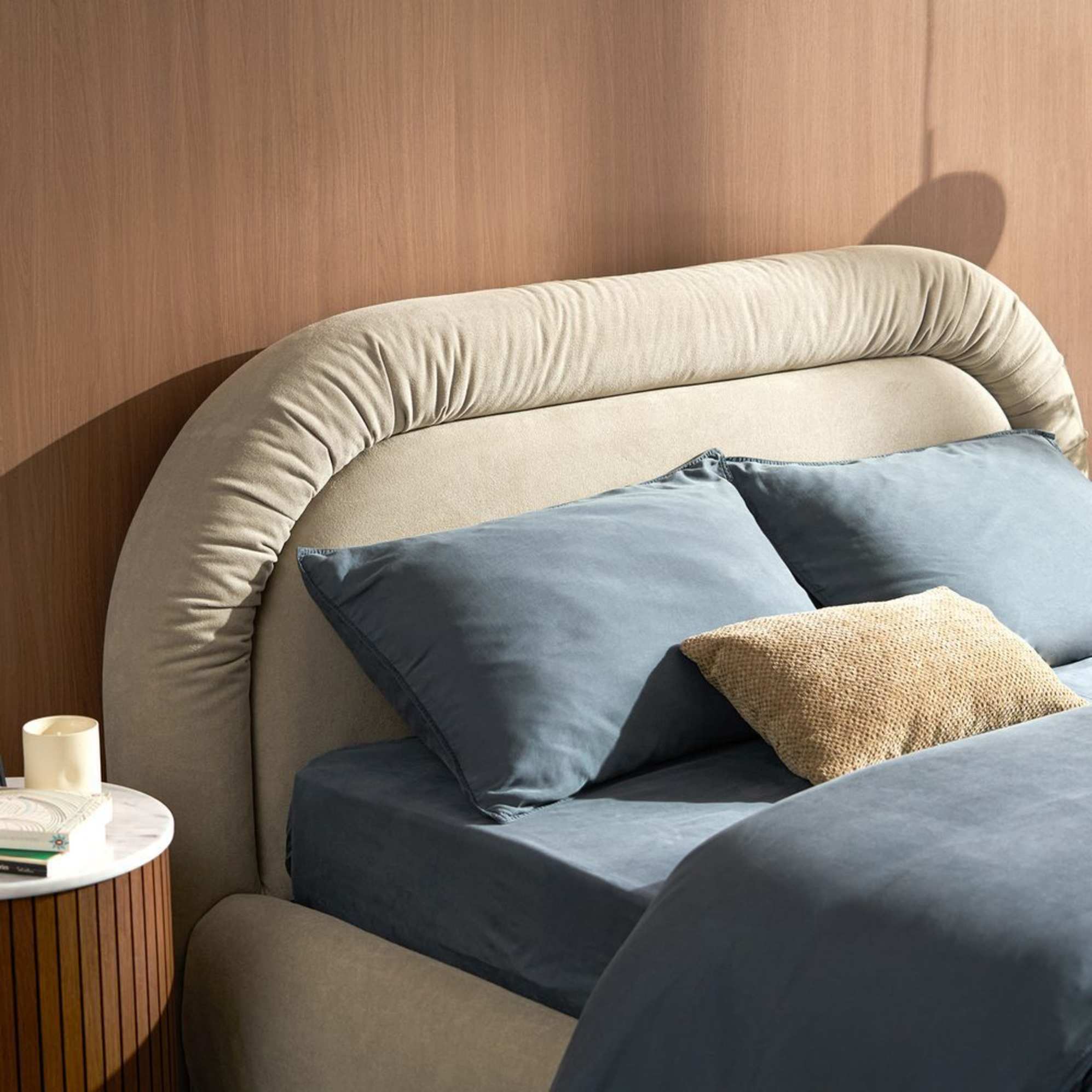 A bed with an upholstered headboard and deep blue bedding.