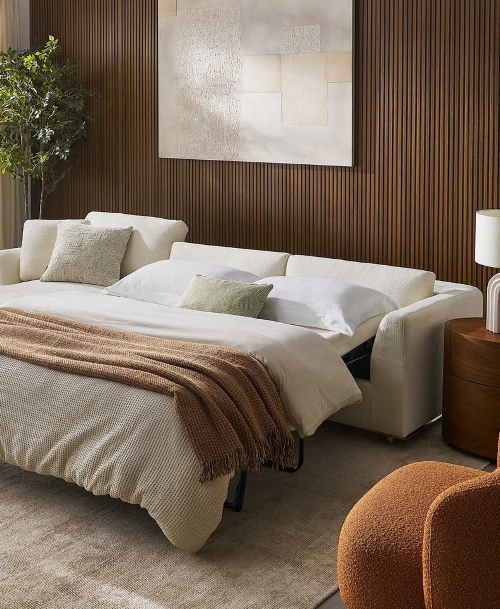 A white chaise sectional sleeper sofa placed in a living room.