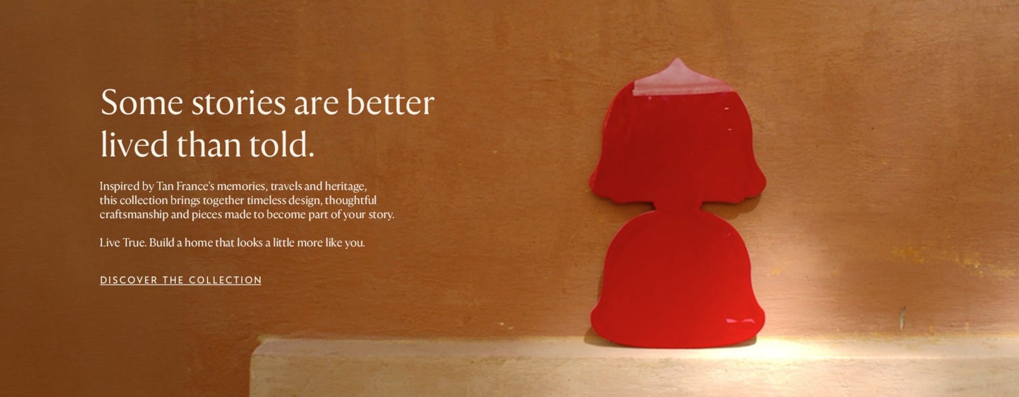Tan France collection, showing a red table lamp against a warm terracotta wall