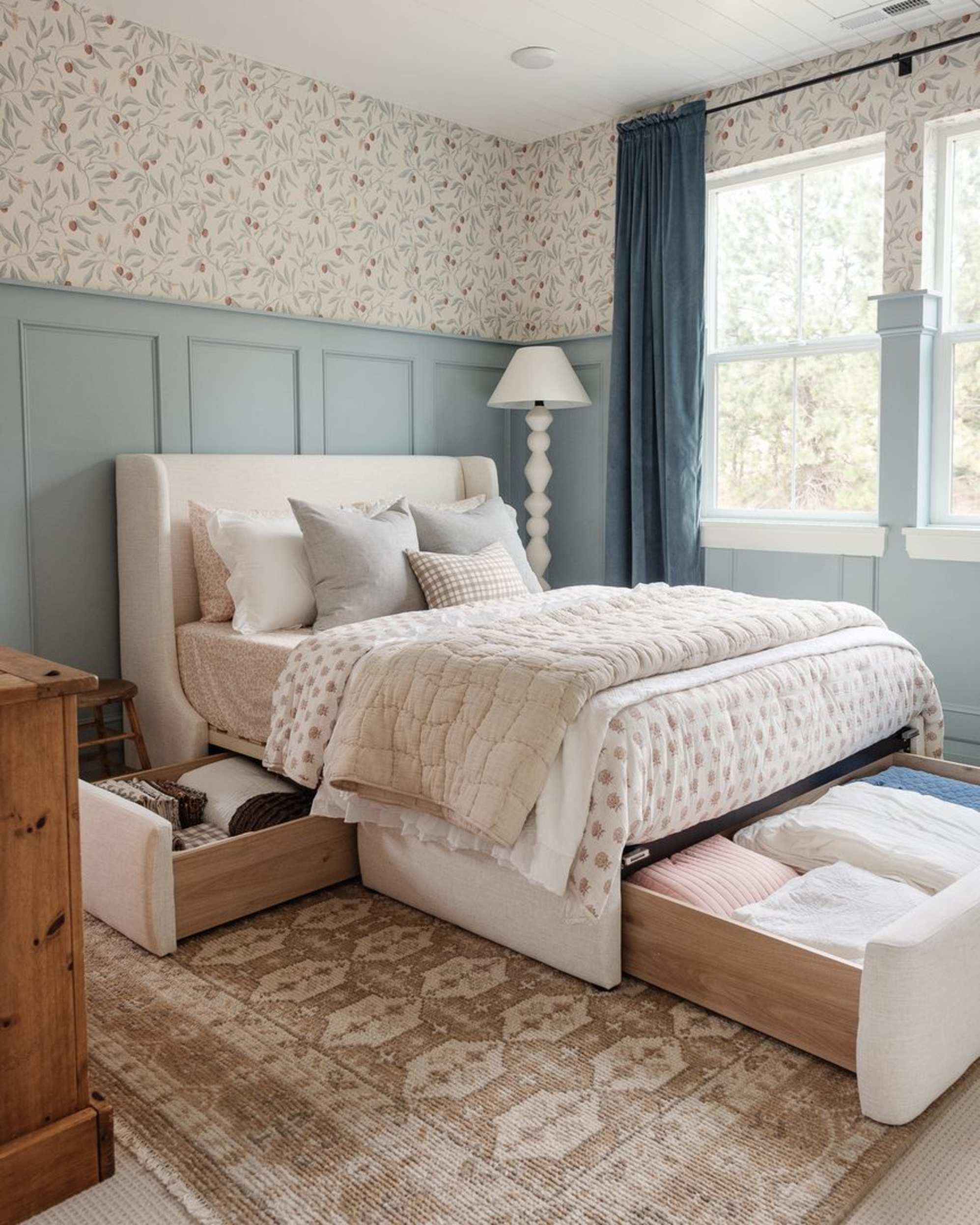 A storage bed with its built-in drawers pulled out to reveal bedding and linen stored in the compartments.