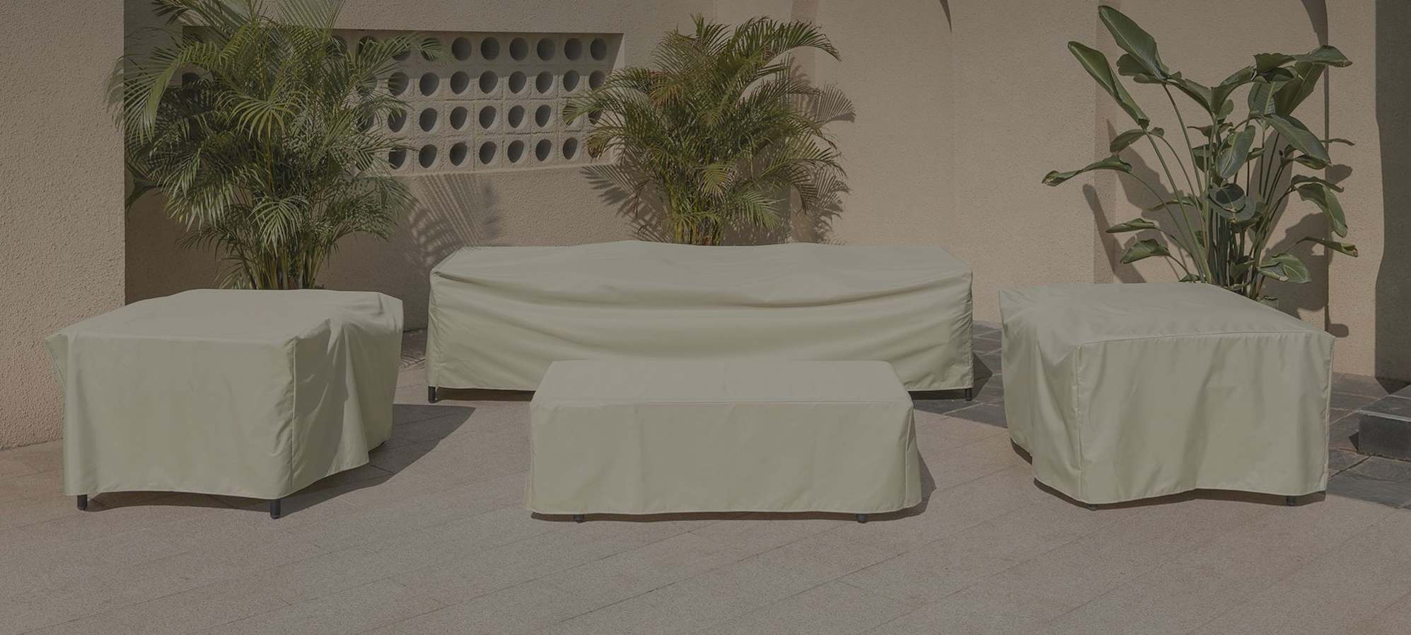Outdoor furniture covers placed over a sofa, coffee table, and two armchairs.