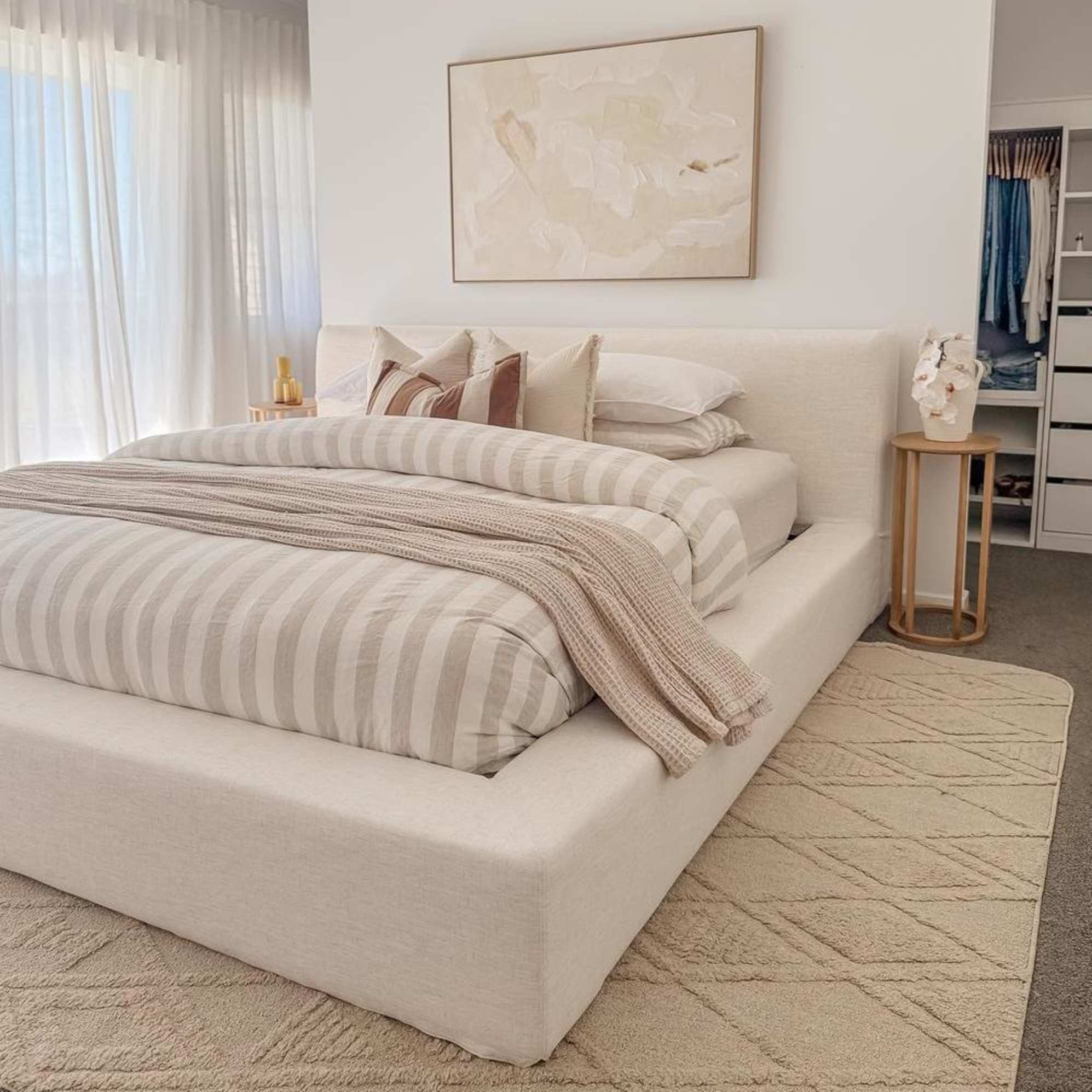 A storage platform bed placed against a wall with an artwork hanging above the bed.
