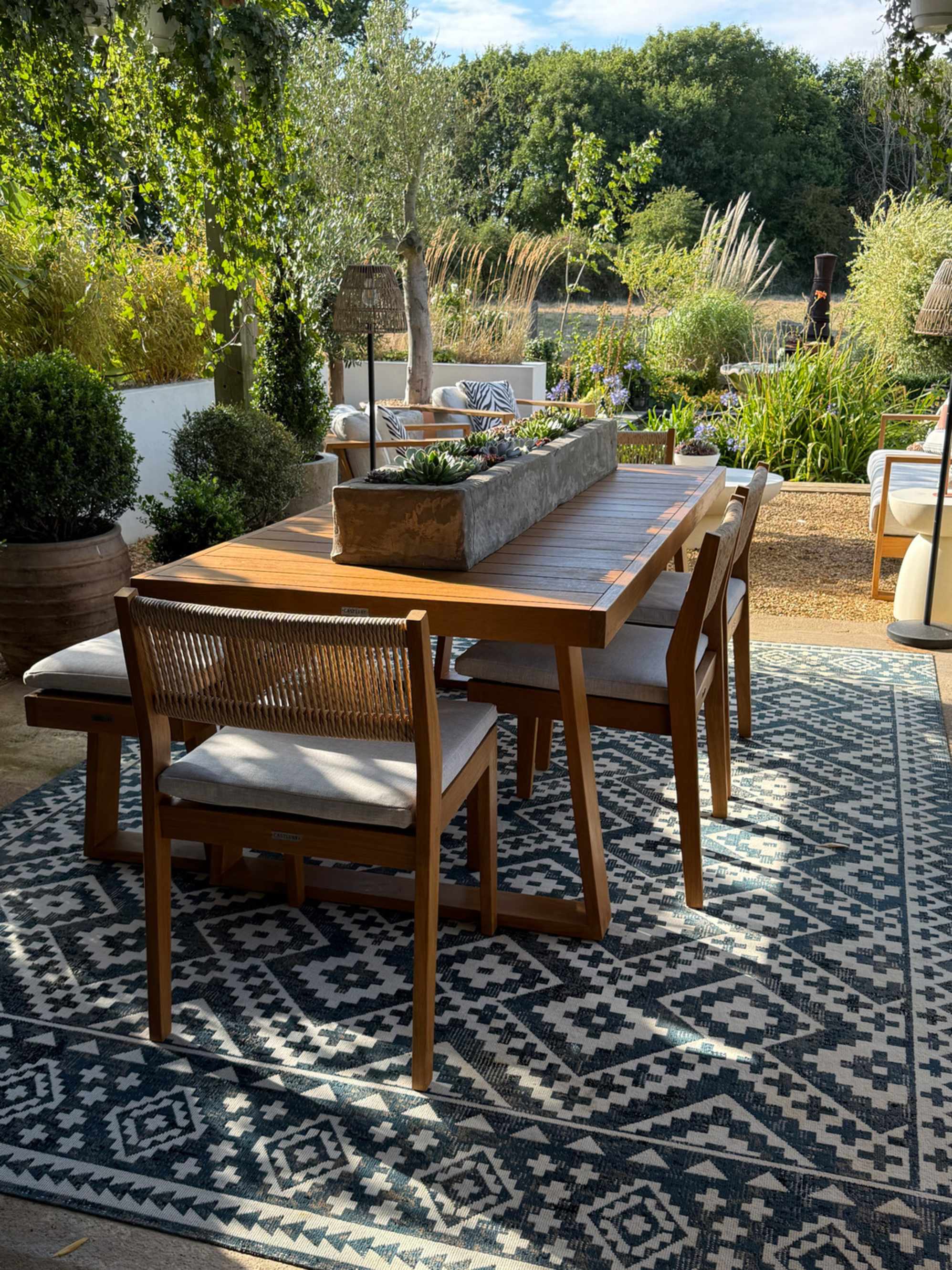 A teak garden dining set with a planter placed in the middle of the table.
