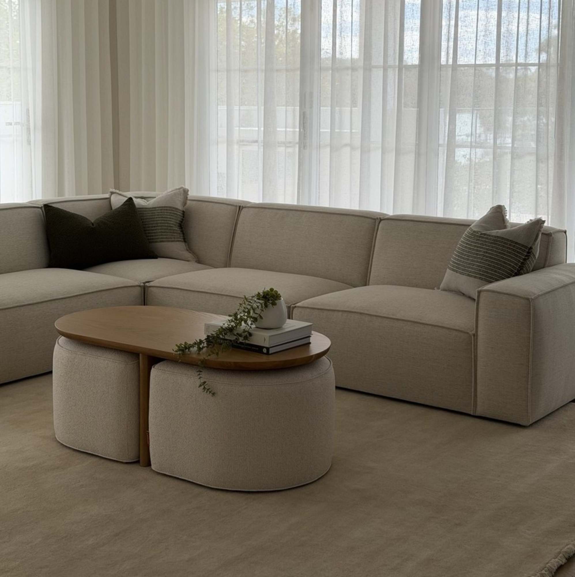 A white L-shape sectional sofa placed in the living room with a nesting coffee table.
