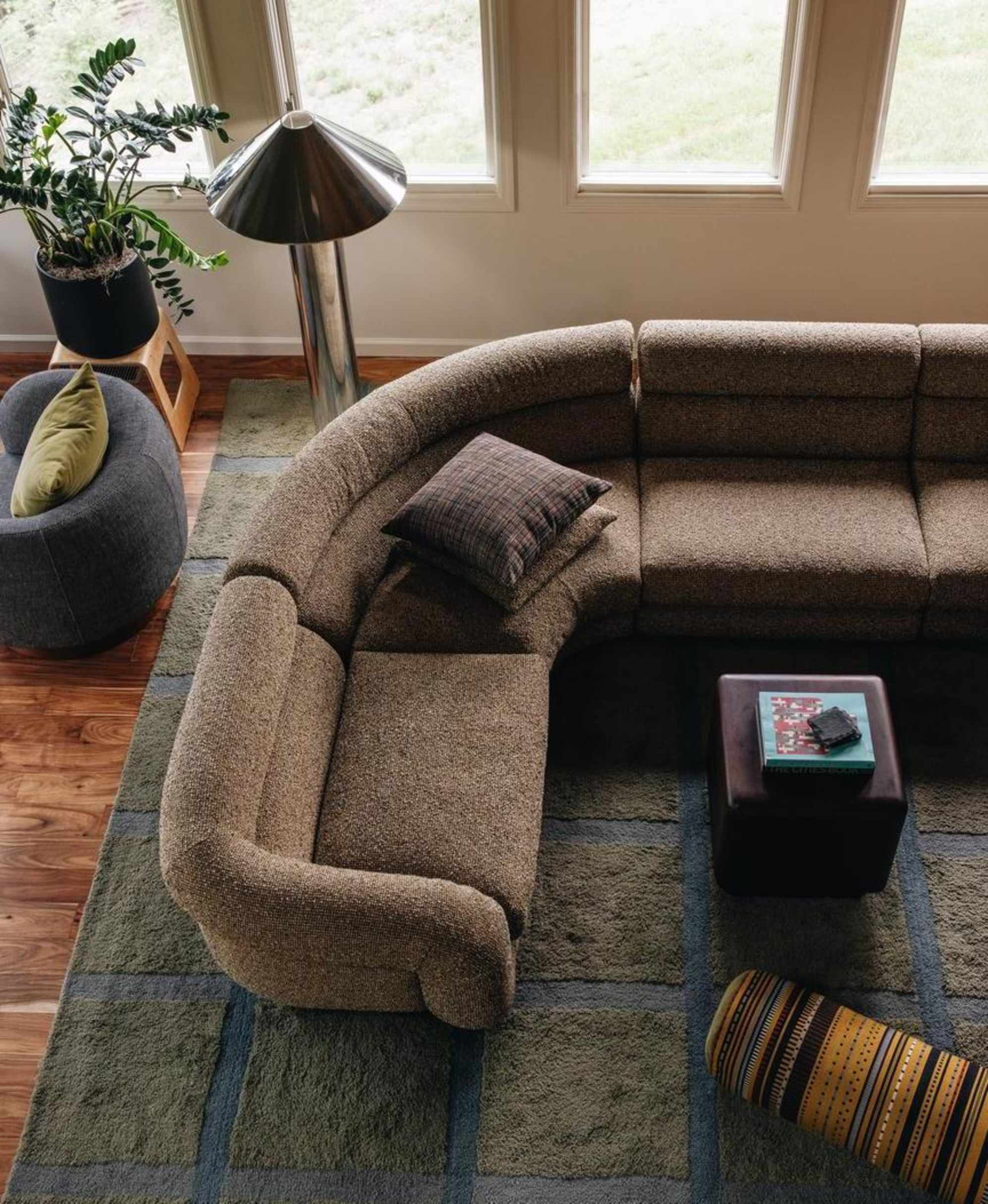 A moss green performance fabric L-shape sectional sofa placed atop a checkered green area rug.