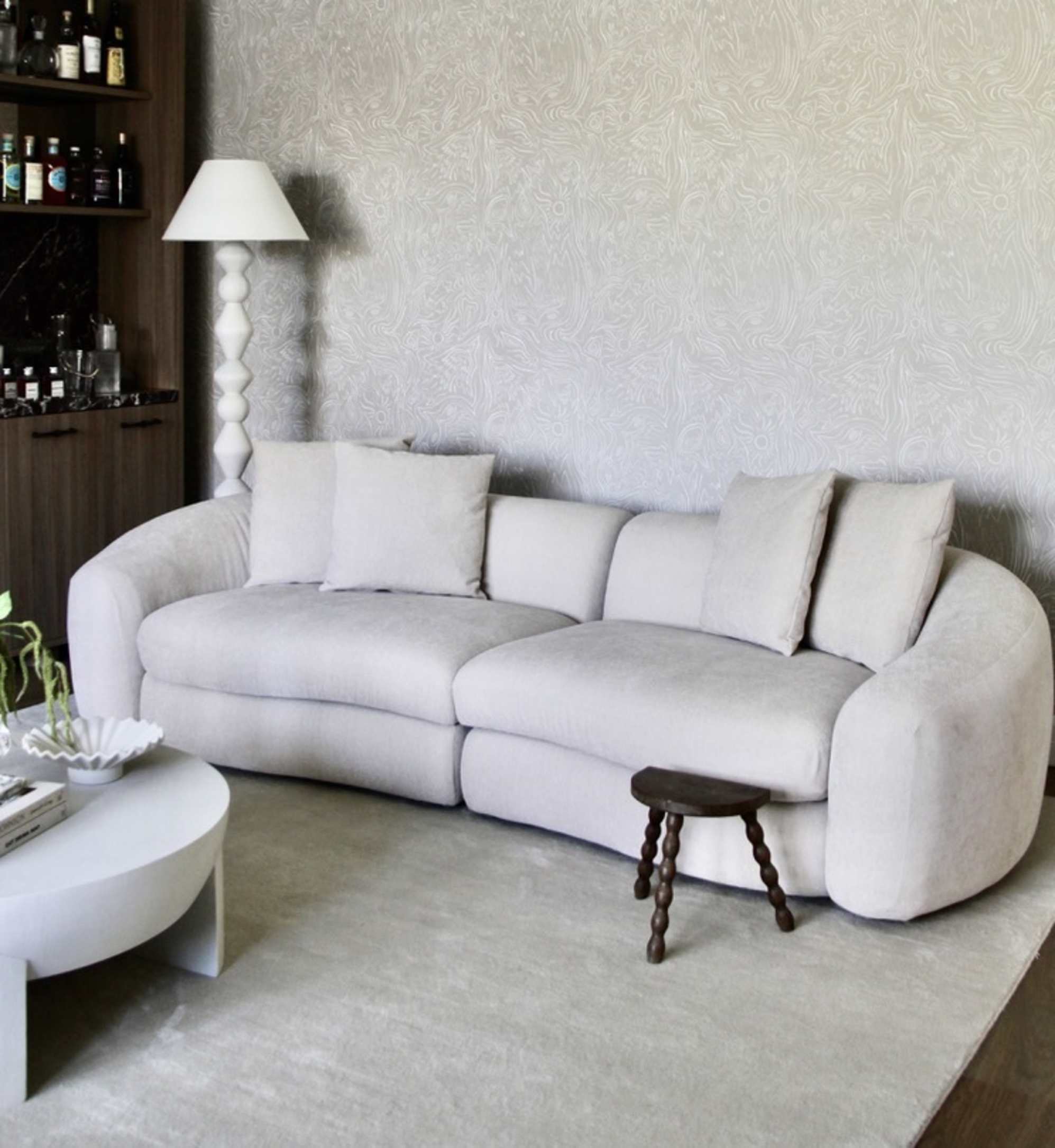A performance fabric sofa placed against a wall with a sculptural floor lamp beside it.