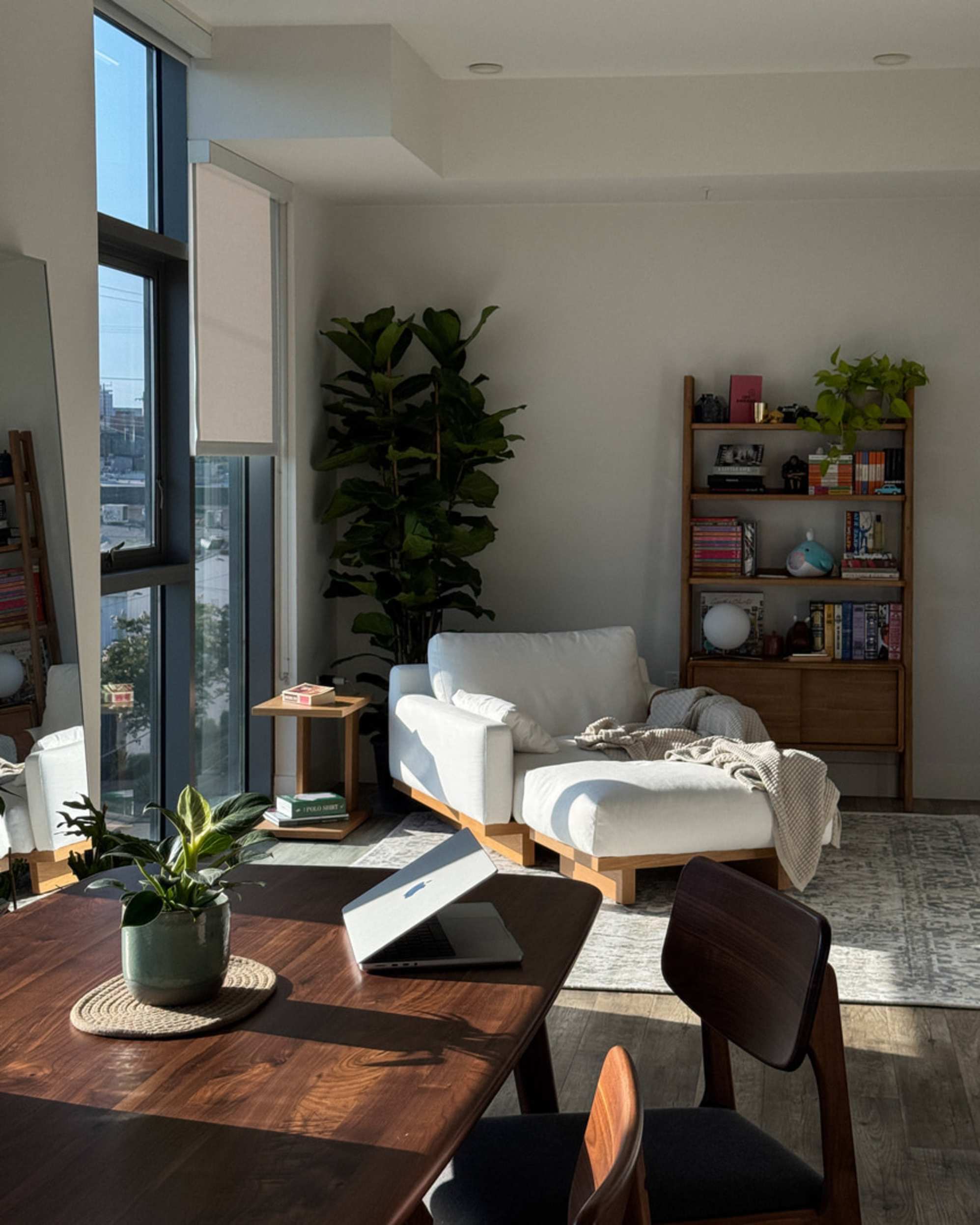 A white armchair with a matching ottoman placed by the window in an apartment.