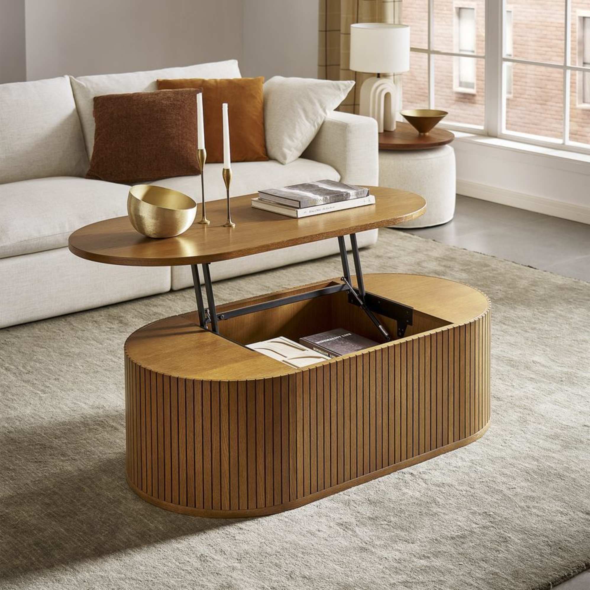 A lift-top coffee table with books, decor, and candles placed on the extended tabletop. 