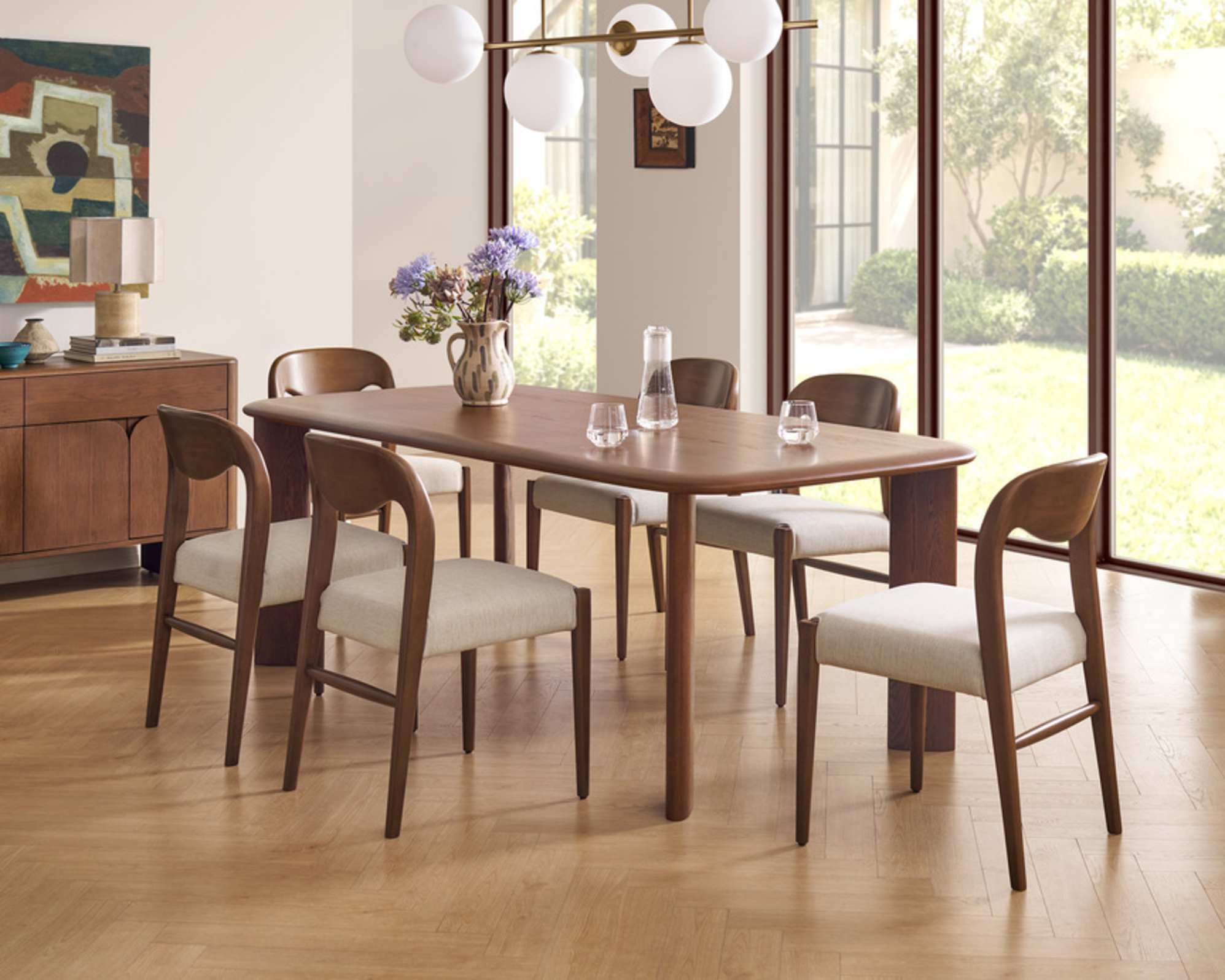A solid oak dining table with six woven dining chairs.