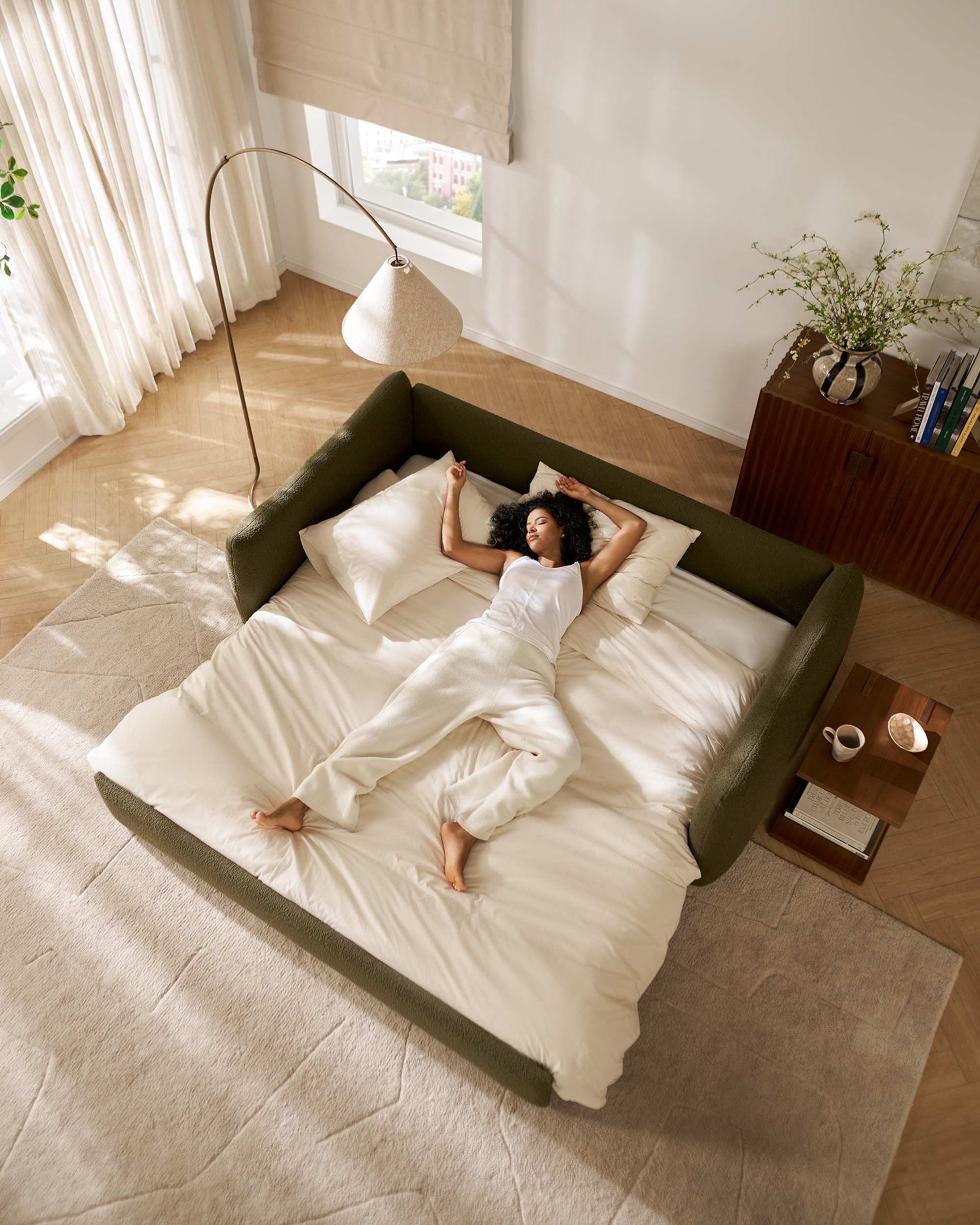 A person sprawled out on a moss green sleeper sofa.