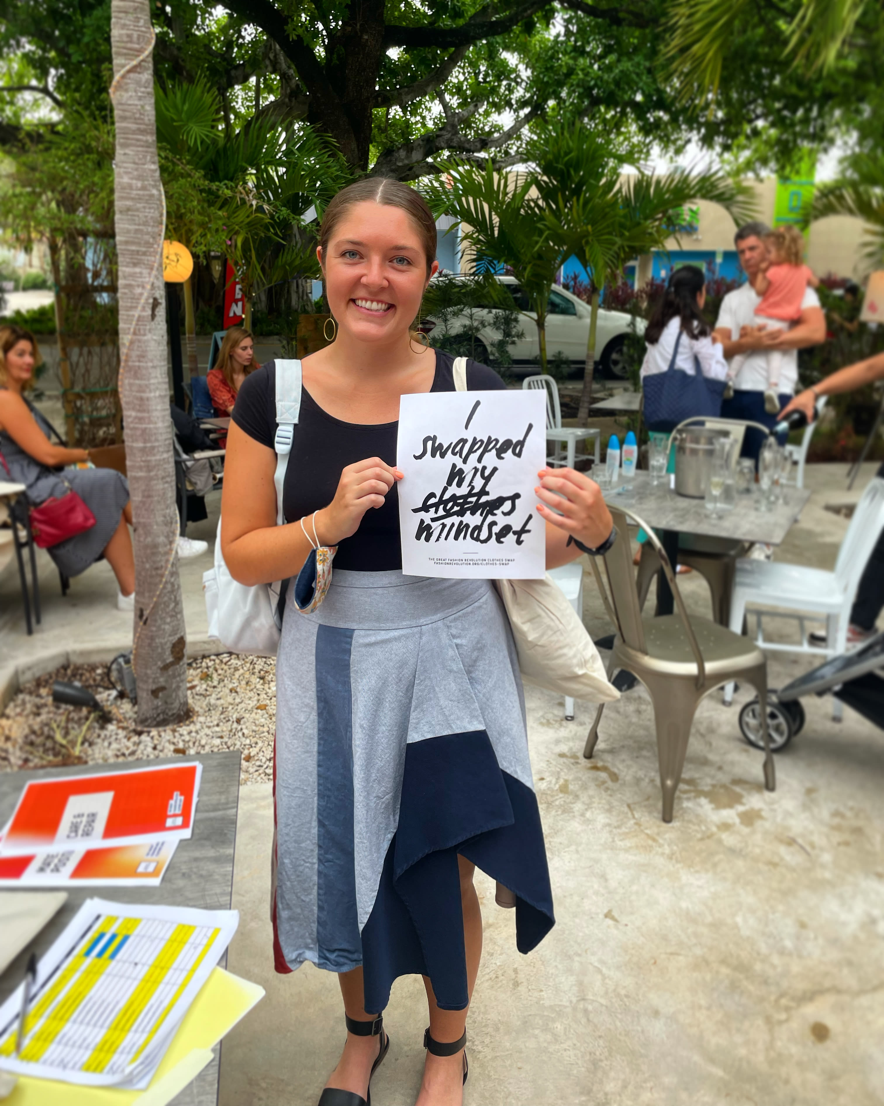 Alexina sostiene un cartel que dice "Canjé mi mentalidad" con la palabra "ropa" tachada