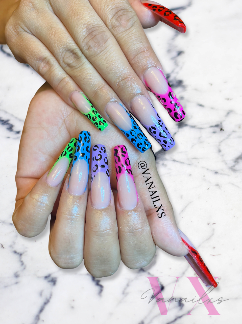 A picture of a client's nails with long acrylics in neon cheetah print.