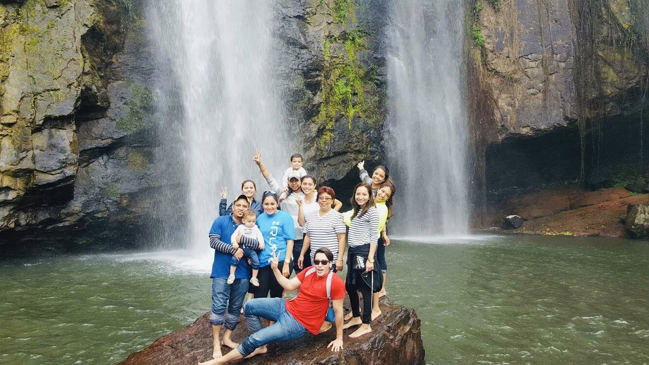 Bosco and family posing on a rock in front of a waterfall