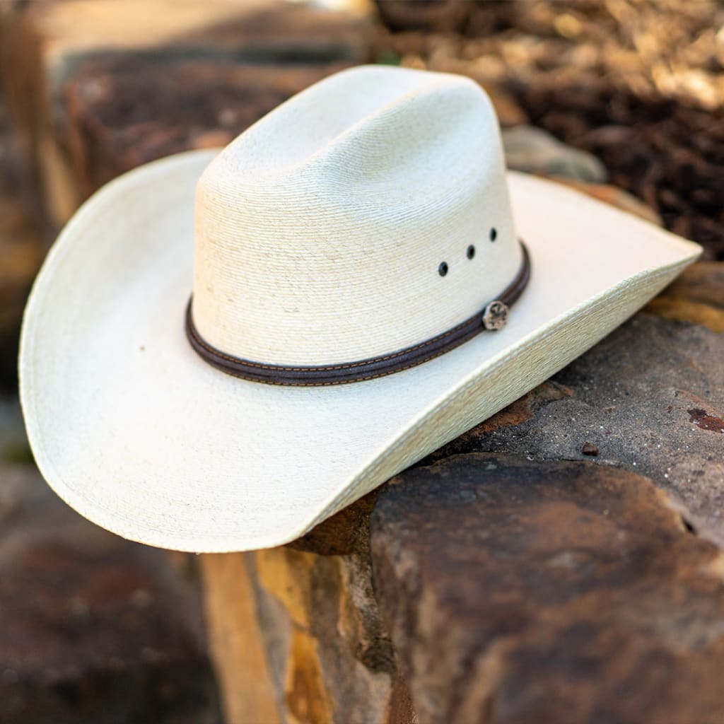 A white Palm Leaf cowboy hat with a brown leather hat band.