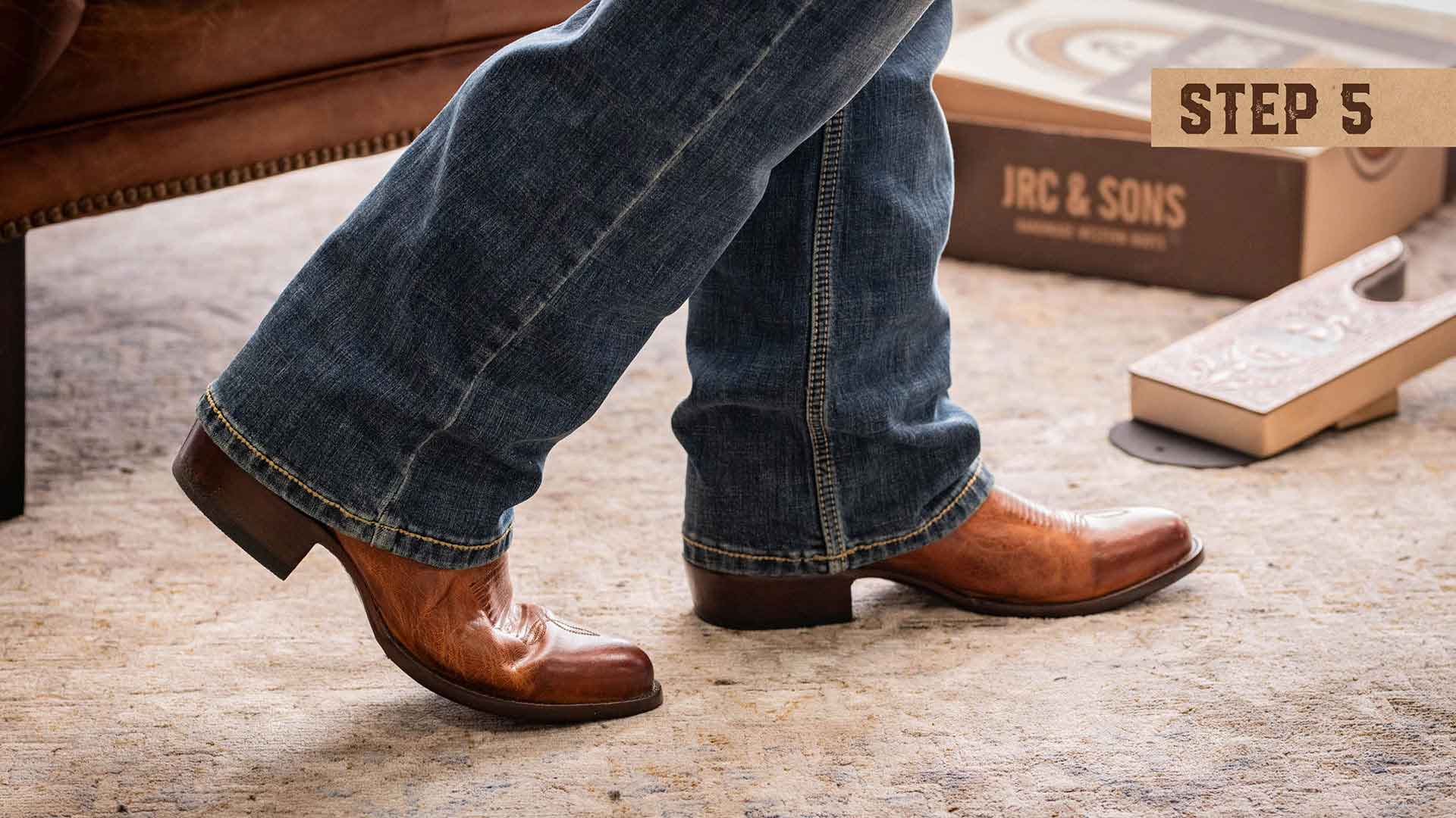 Step five, shows someone walking around with their brown leather cowboy boots, with a JRC & Sons boot box on the ground right next to a boot hook to help remove the boots after checking for appropriate heel lift and comfort.