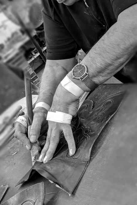 Skilled artisan hands carefully measuring, cutting, and meticulously sewing the vamps and shafts of Black Jack Boots, showcasing precision craftsmanship in boot-making.