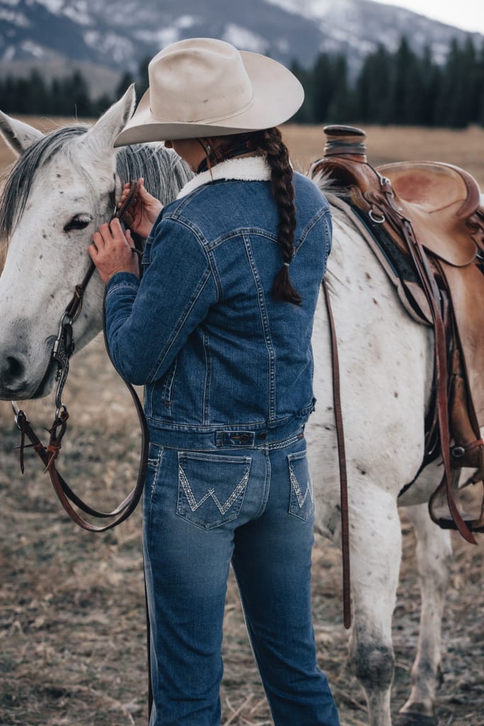 Cowgirl in a Cowboy Hat and Ponytail Making Final Horse Adjustments before Riding.