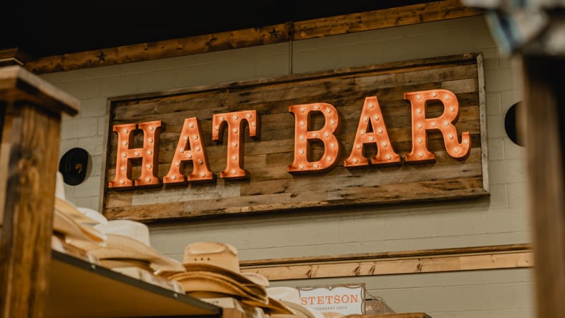 Cavender's Hat Bar, featuring a wide selection of cowboy hats neatly arranged on wooden shelves.