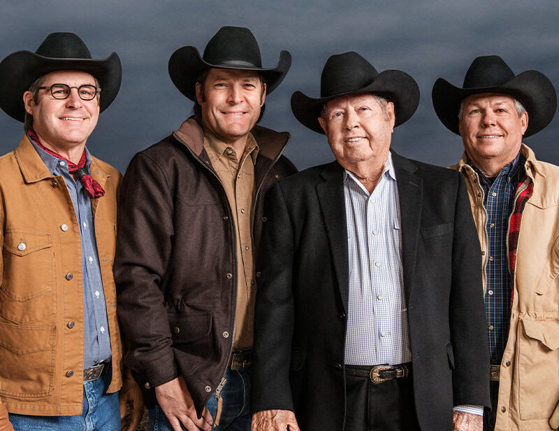 Four members of the Cavender Family, James, Joe, Mike, and Clay, donning stylish felt cowboy hats and beaming with warm smiles.