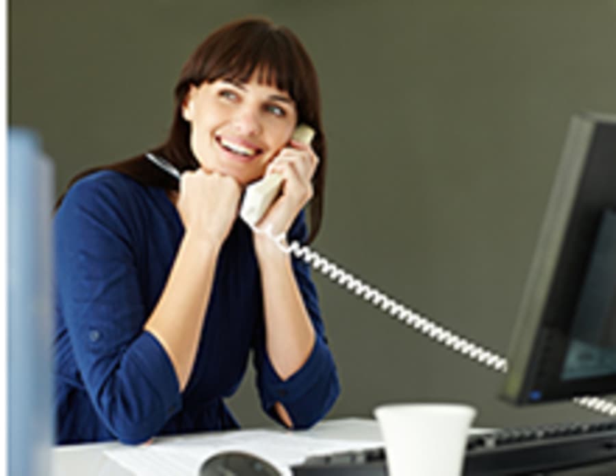 Vrouw achter computer aan de telefoon