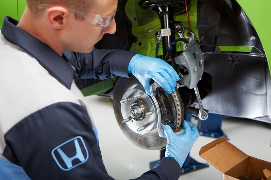 Honda service technician replacing brake pads