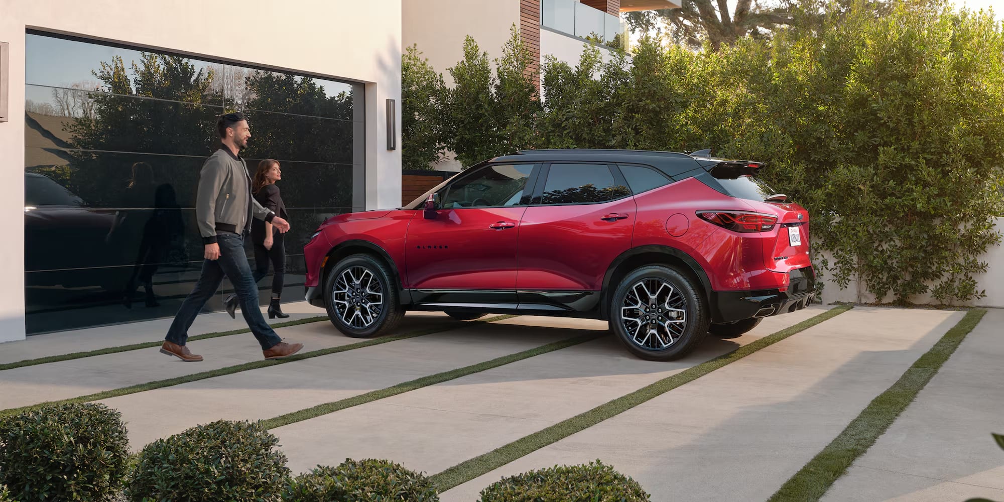 People walking next to red chevrolet blazer