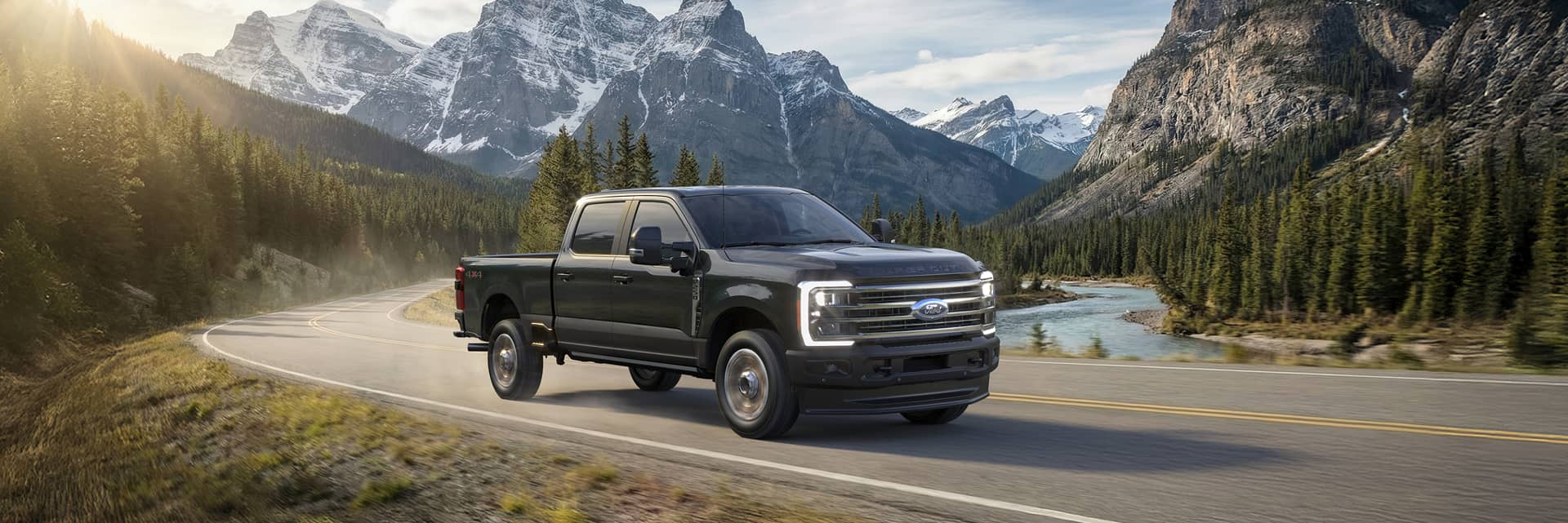 A Ford Super Duty F-250 driving on road in front of mountains and river