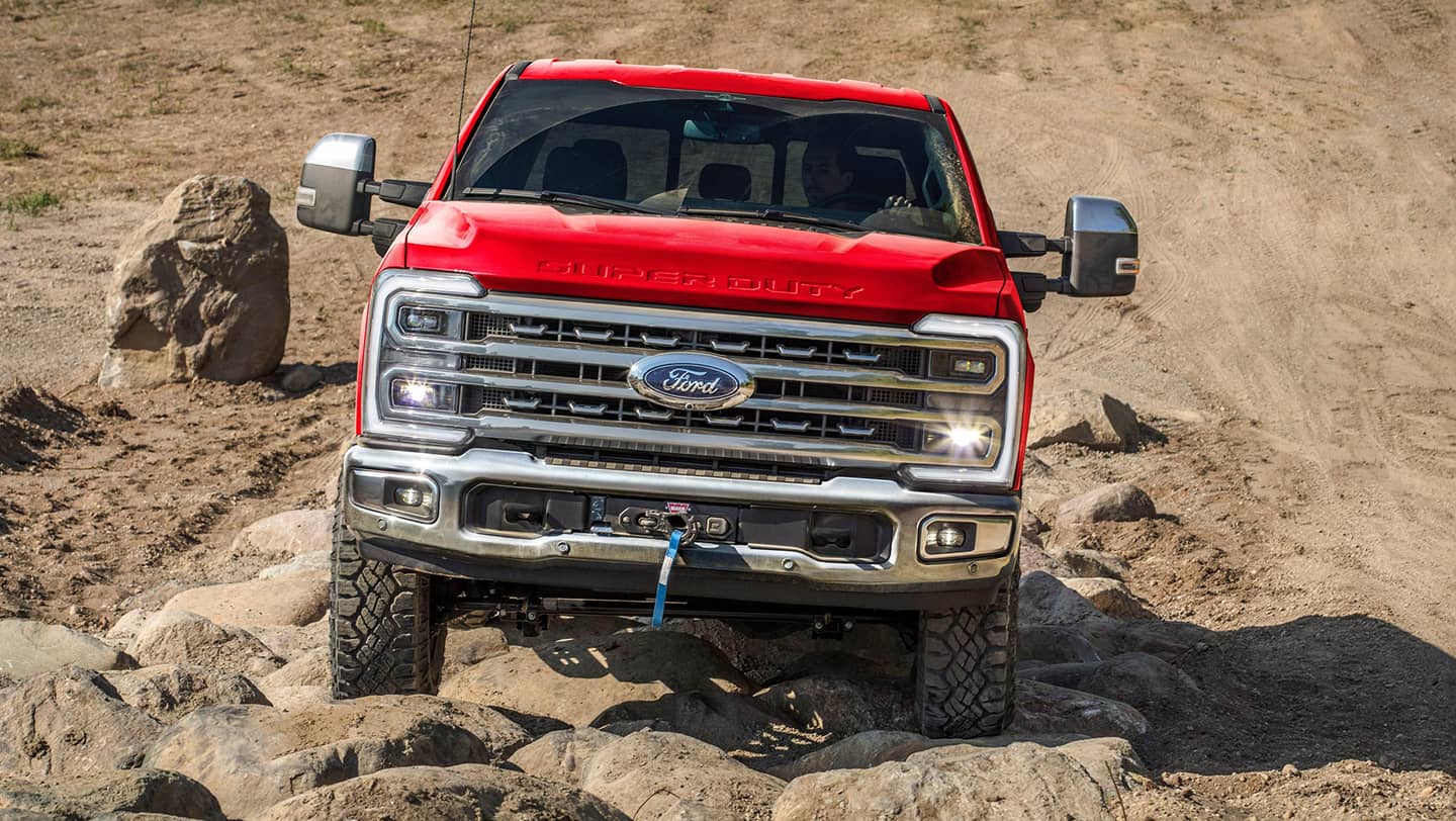 front view of red ford super duty f-250 driving through sand