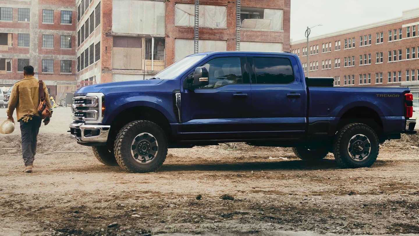 construction worker walking next to blue ford super duty f-250