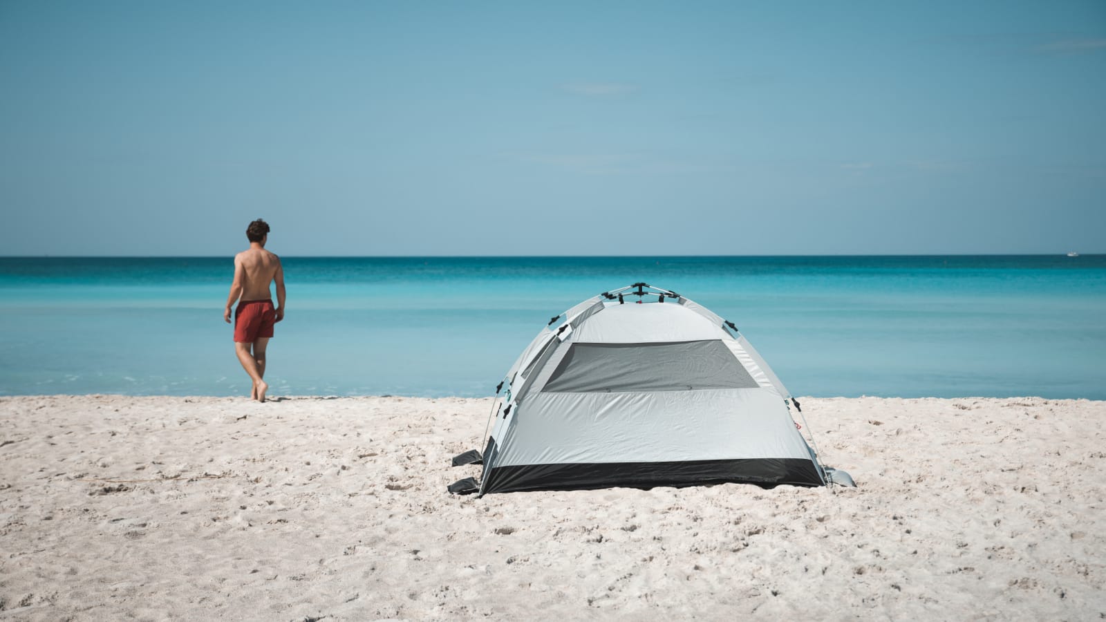 mann_am_strand_neben_qeedo_strandzelt