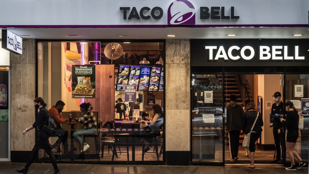 a taco bell restaurant with people walking in front of it