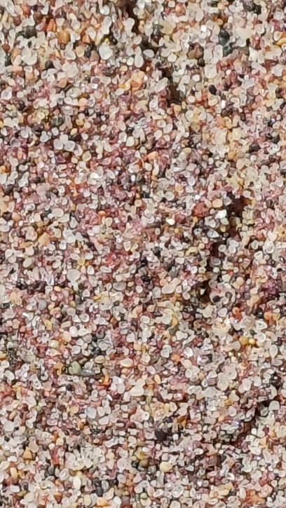 A klečeli v růžovém písku složeném jakoby že skleněných korálků