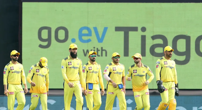 Chennai Super Kings (CSK) players in yellow jerseys walking together on the cricket field during an IPL match.
