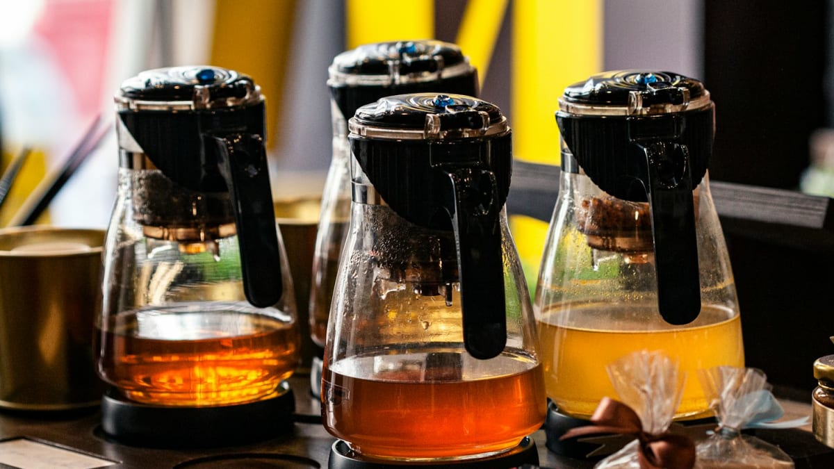 Glass tea brewers with black and herbal tea on a cafe counter