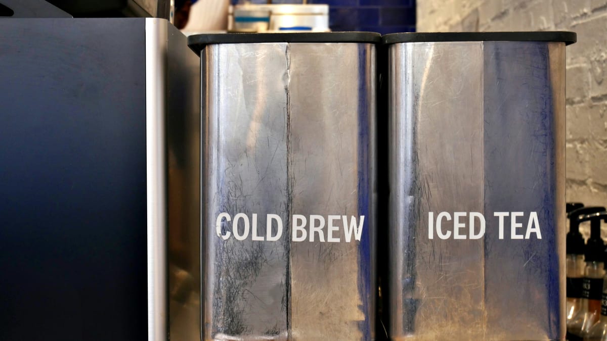 Commercial iced tea and cold brew dispensers behind a cafe counter
