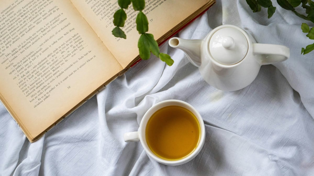 A cup of bedtime tea and an open book on a bed
