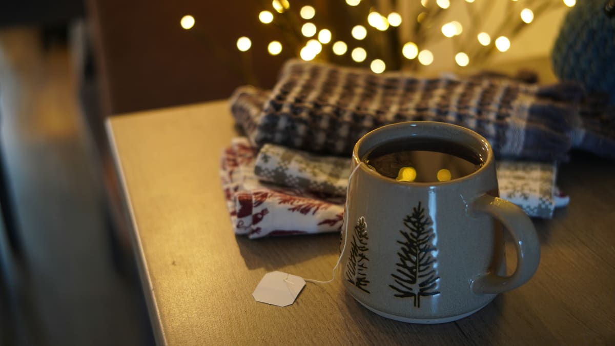 Warm mug of tea with Christmas lights in the background