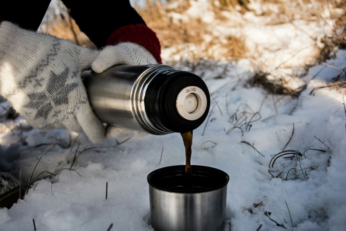 Pouring hot tea from a flask on a winter day