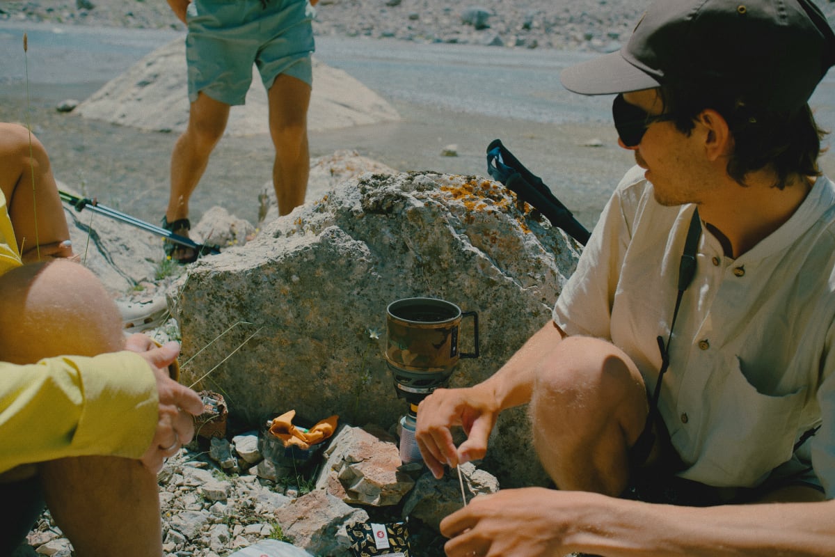 Campers using a portable stove on a riverbank