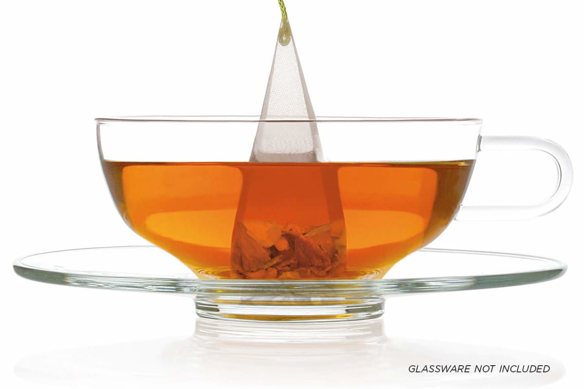 Tea Forte pyramid infuser steeping in a glass teacup and saucer