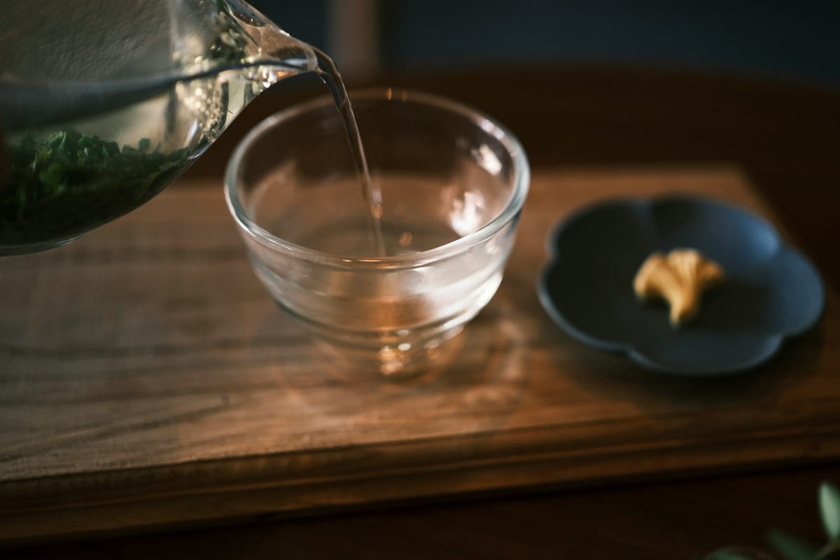 Hot tea poured into a clear glass cup, showing a clean, bright color