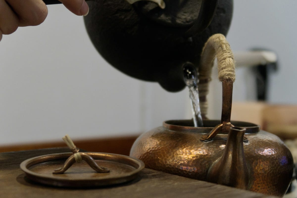 Pouring hot water from a kettle into a teapot