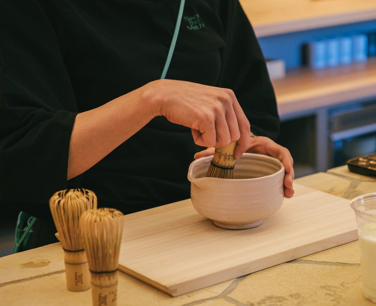 Whisking foamy matcha in a handmade ceramic chawan