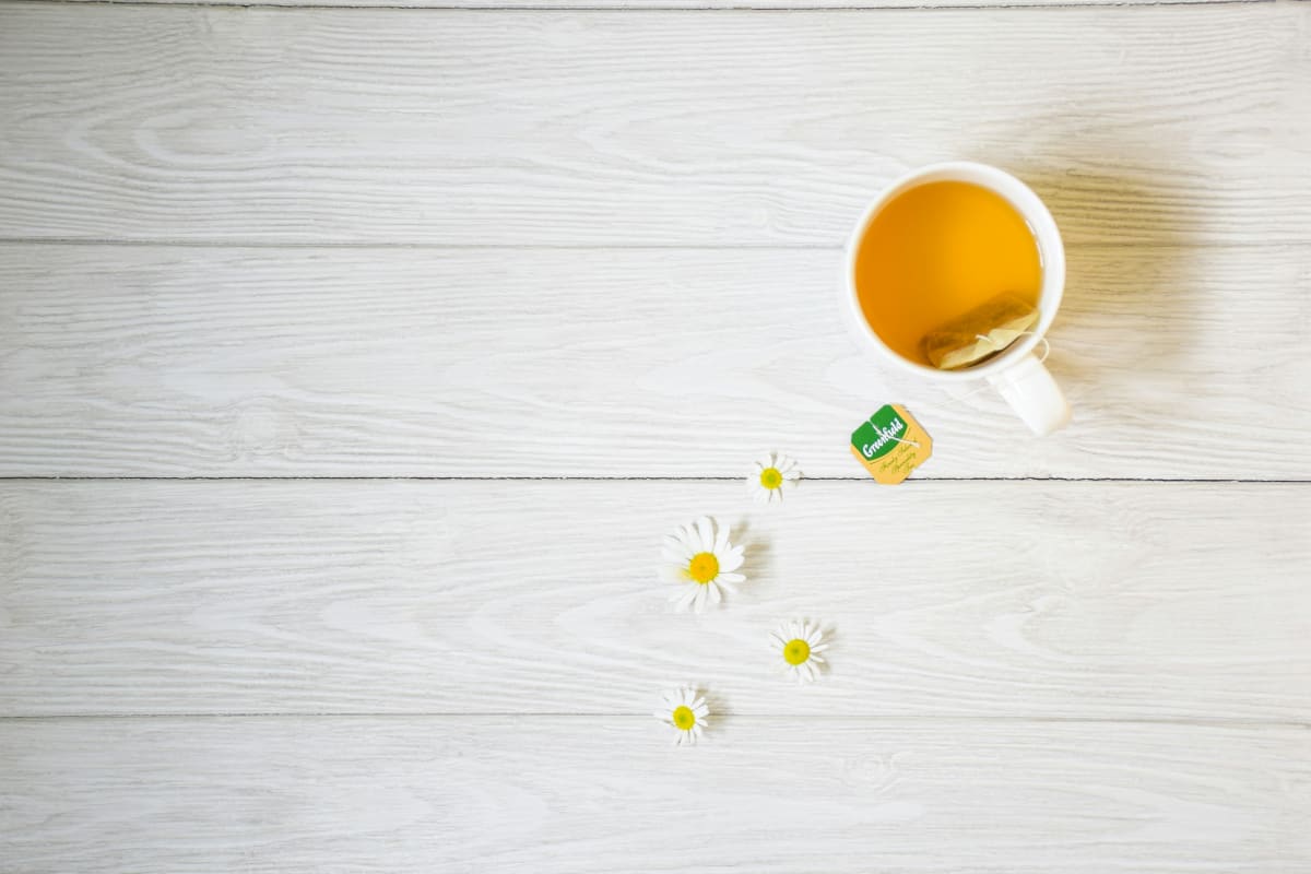 Cup of chamomile tea with daisies on a nightstand