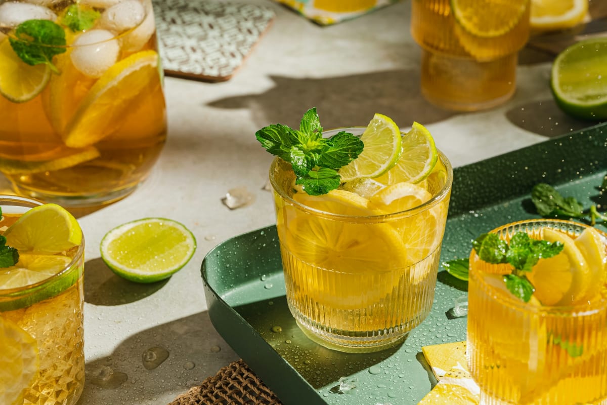 Tall glasses of amber iced tea with lemon, lime, and fresh mint