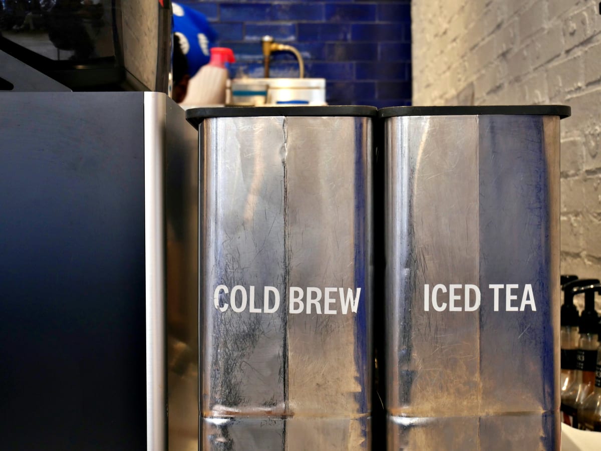 Commercial iced tea and cold brew dispensers behind a cafe counter