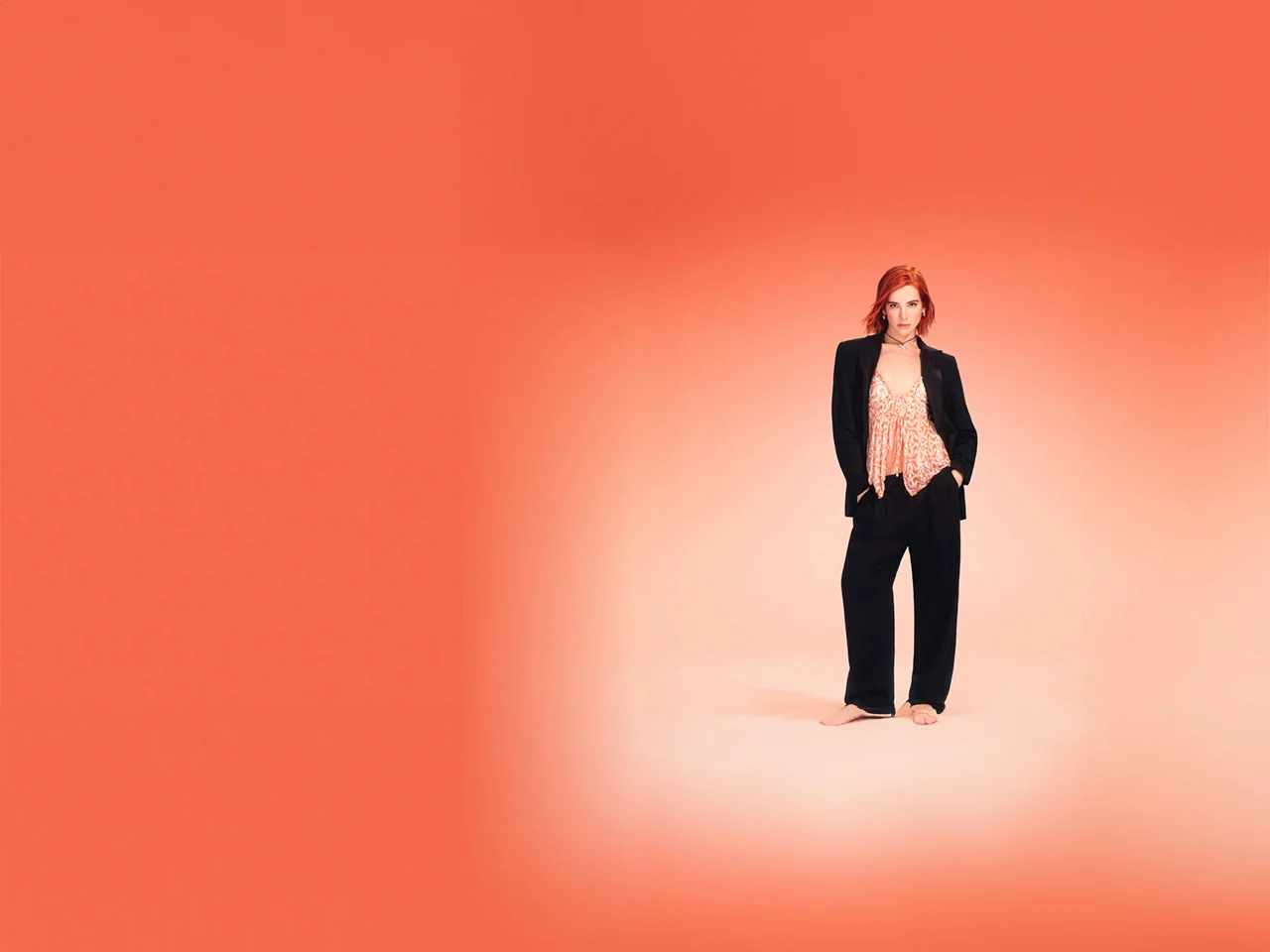 Chica con traje negro y top en color naranja sobre fondo naranja