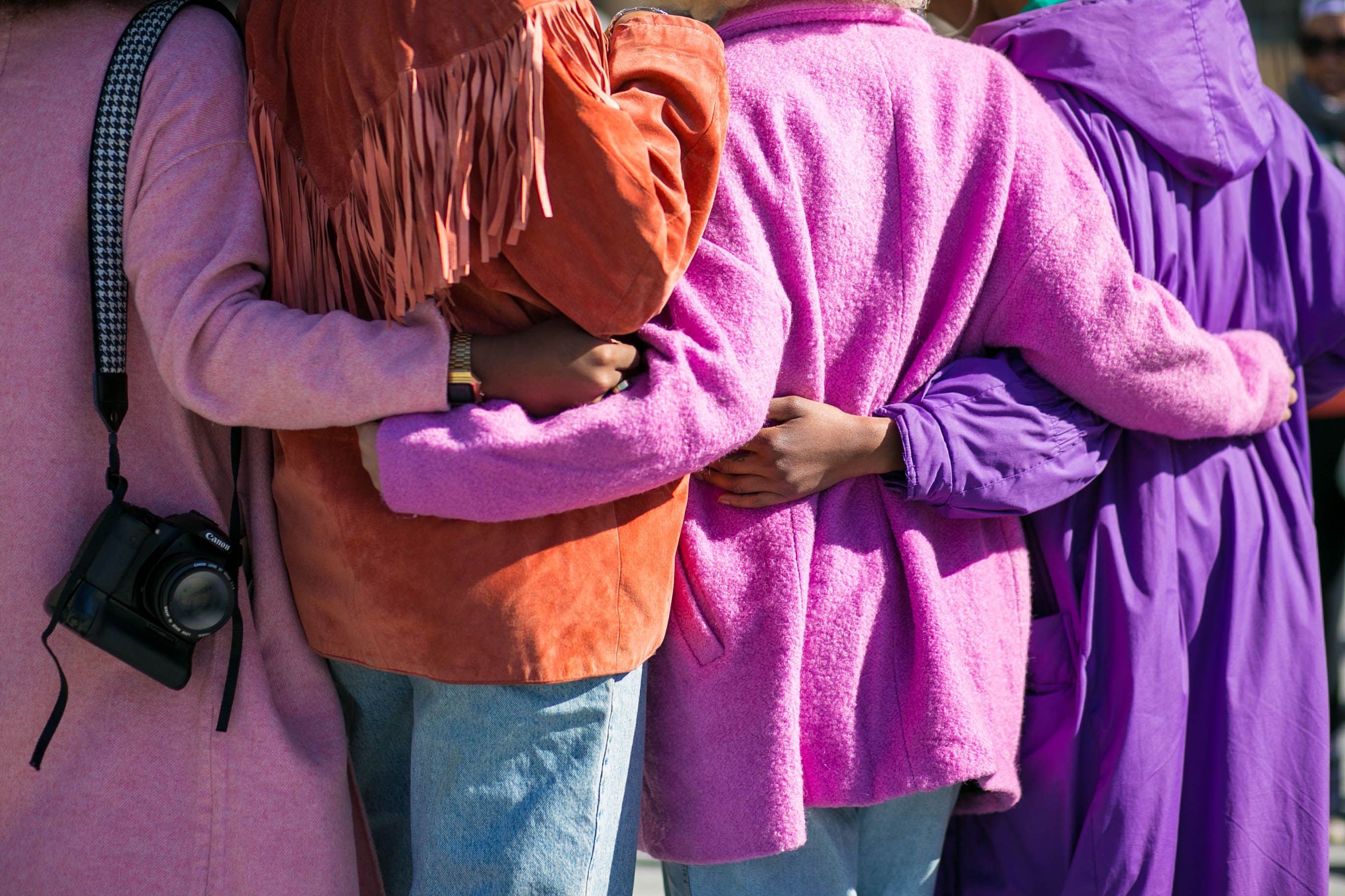 People dressed in colours are hugging and holding each other. People dressed in colours are hugging and holding each other.